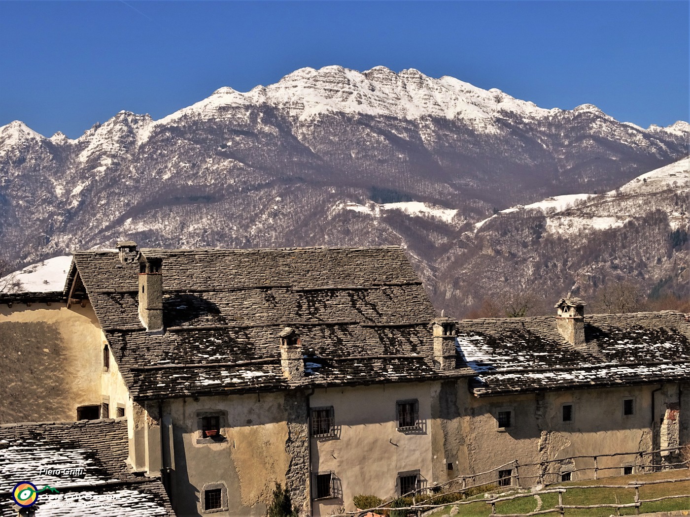 09 Sciolta le neve sui tetti a piode del borgo di Arnosto, ancora ben imbiancato il Resegone.JPG